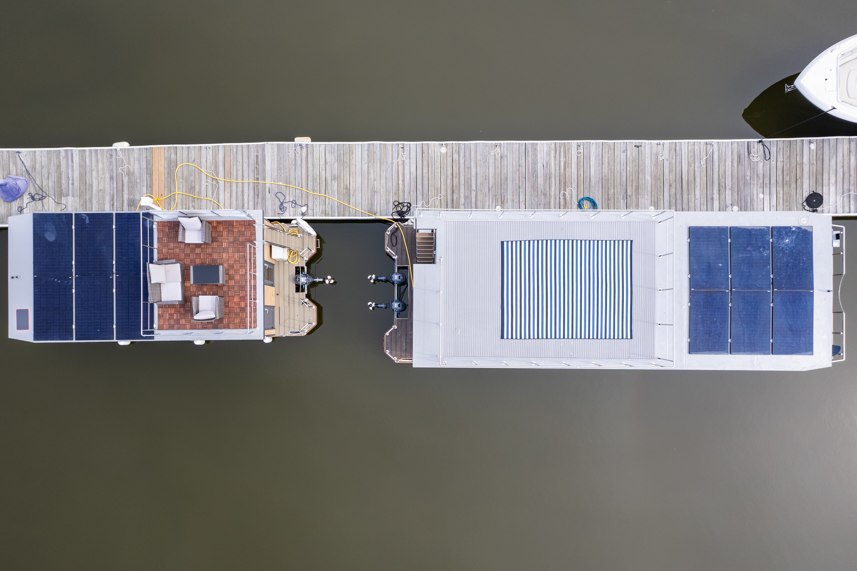 A dock with two boats—one sporting solar panels on its roof. 