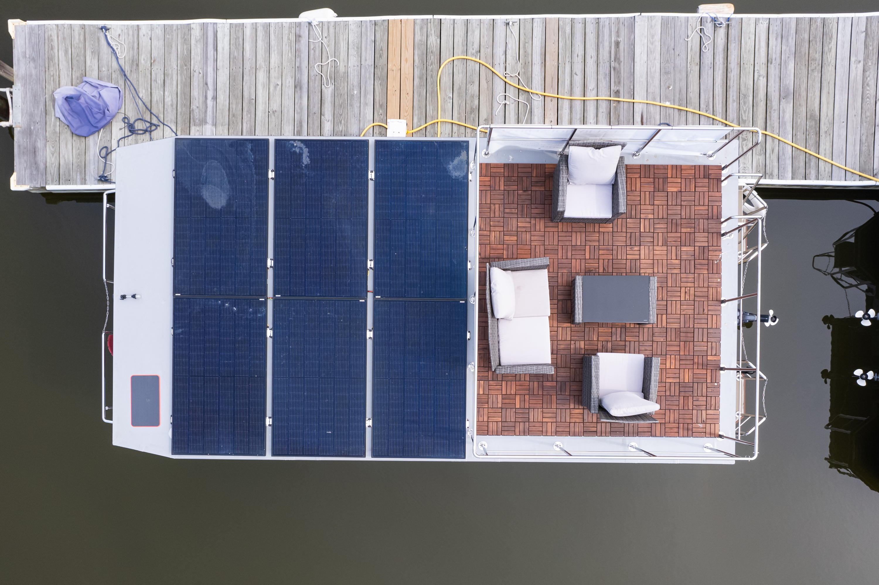 A dock with a boat—it is sporting solar panels on its roof. 