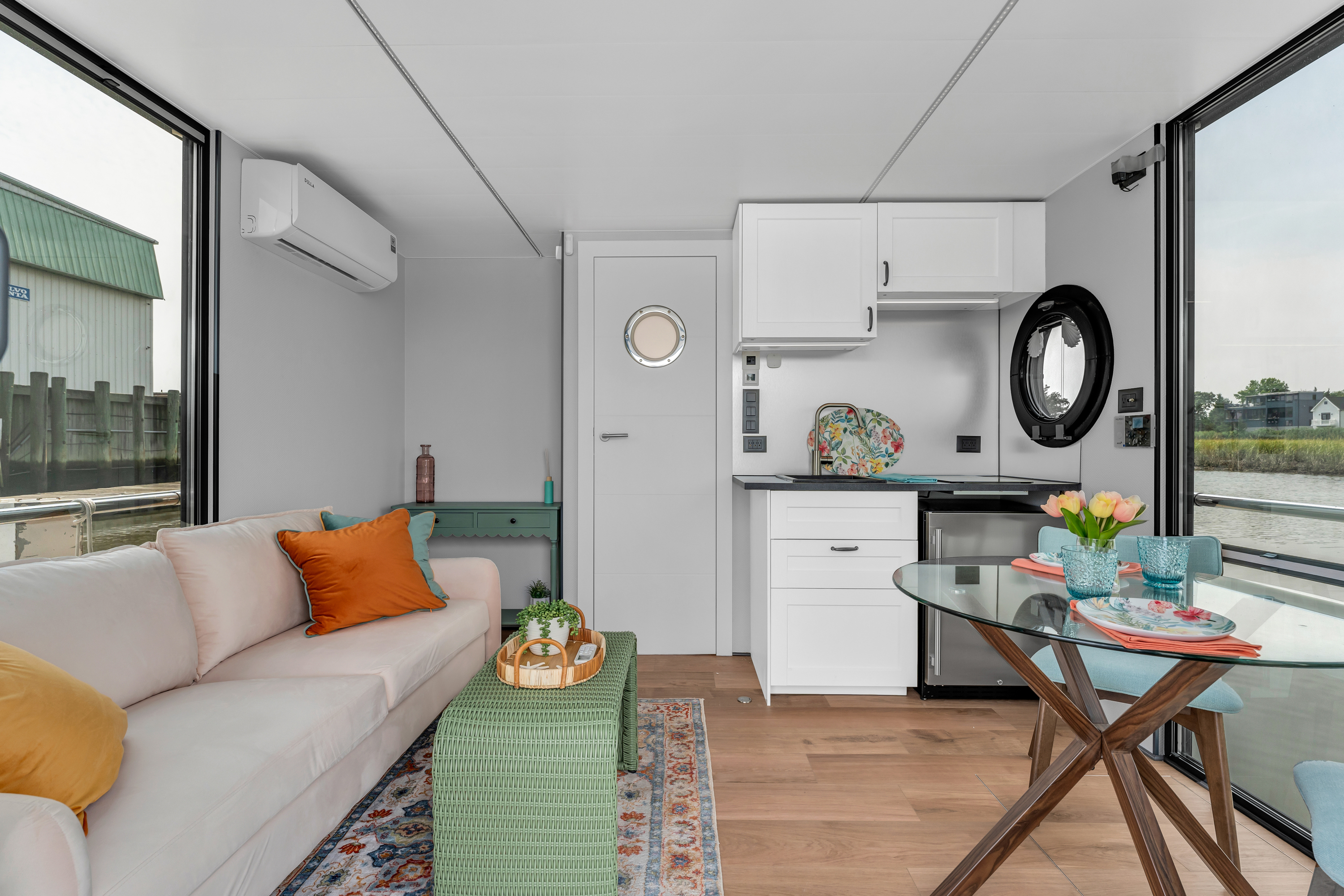 A modern compact kitchen with white appliances, a small dining area, and a cozy living space with a sofa.