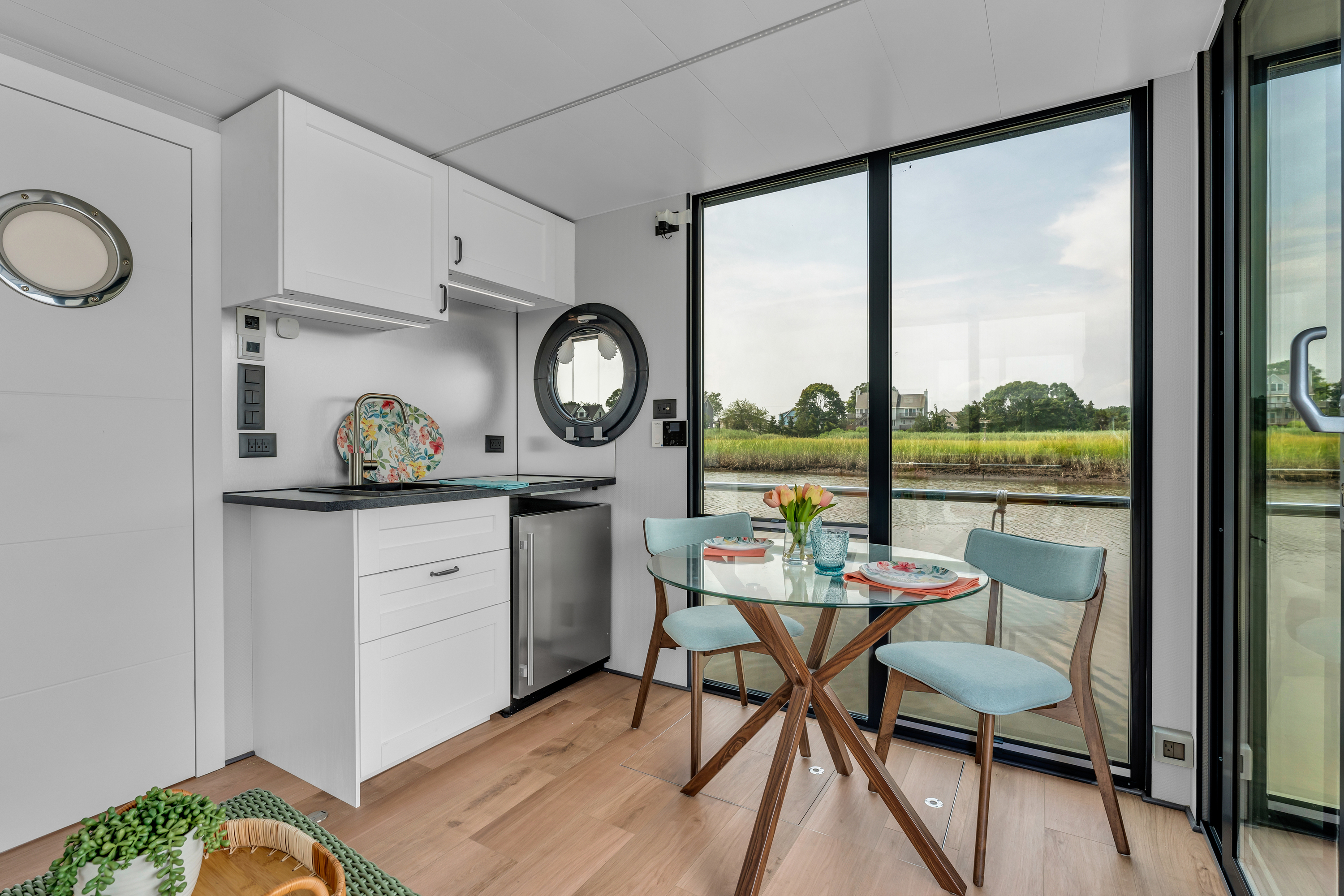 A modern compact kitchen with white walls, a small dining area, and a cozy living space.