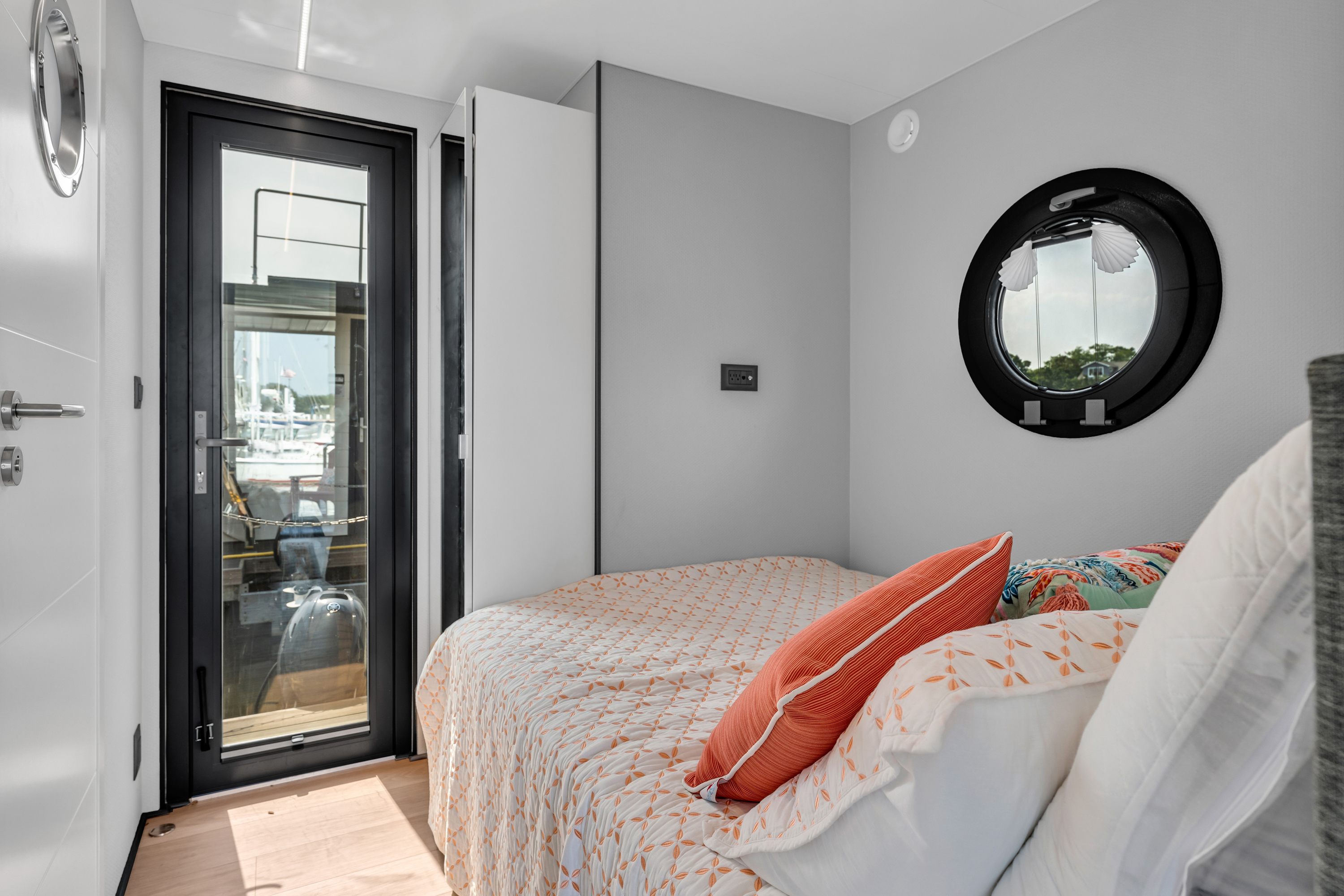 A modern bedroom with a bed, round mirror, and a door leading to a balcony.