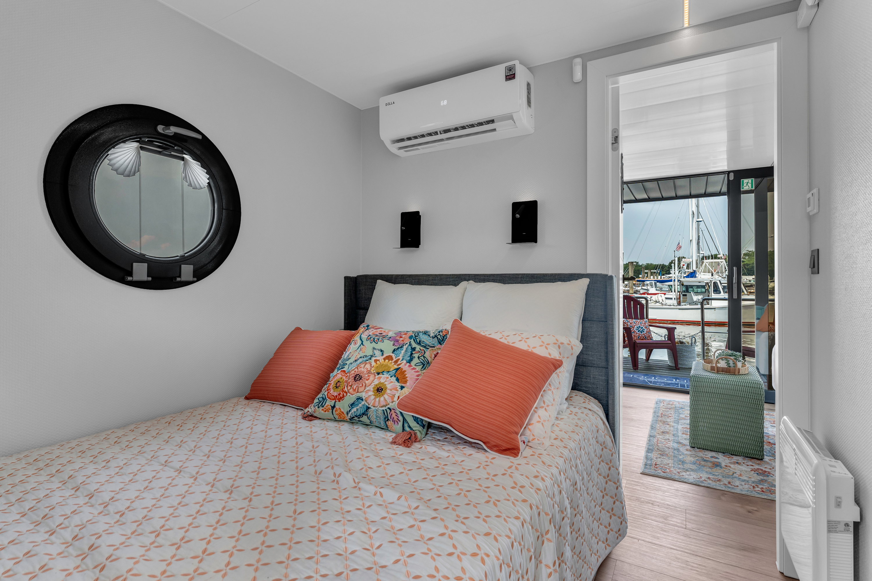 A modern bedroom with a bed, round mirror, and a door leading to a balcony.